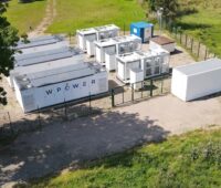 Blick auf Container mit Batteriespeichern auf grüner Wiese.