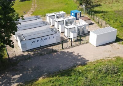 Blick auf Container mit Batteriespeichern auf grüner Wiese.