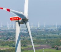 Close-Up einer Windturbine vor dem HIntergrund vieler Anlagen im Flachland.