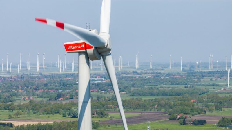 Close-Up einer Windturbine vor dem HIntergrund vieler Anlagen im Flachland.