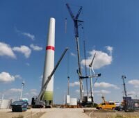 Ein Kran neben dem Turm einer Windenergie-Anlage - Repowering eines Windparks im Burgenlandkreis.