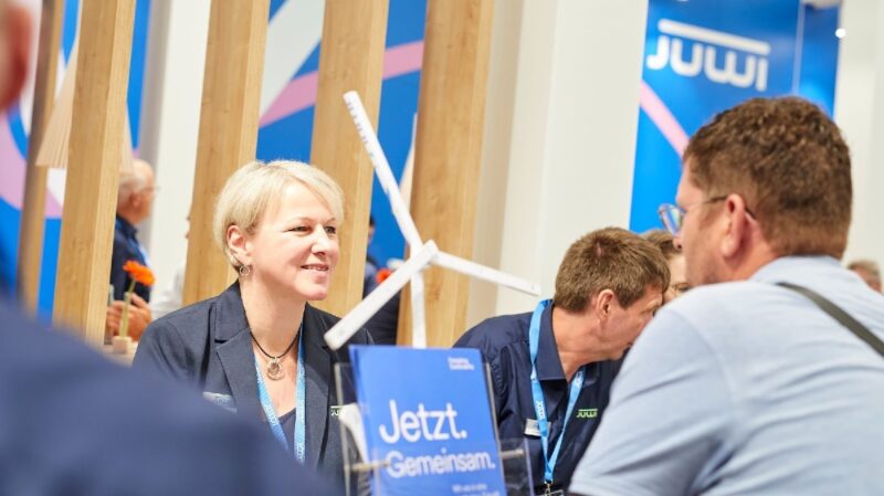 Im Bild zwei Menschen im Gespräche auf einer Messe, Juwi ist auf der Windenergy in Hamburg vertreten.