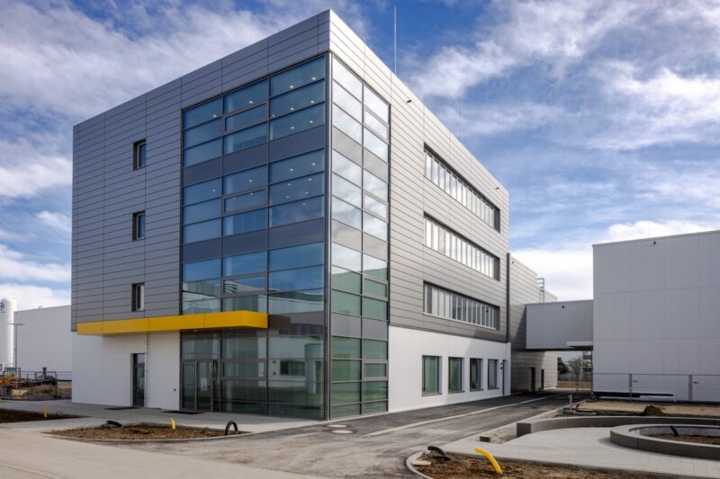 grauer Neubau mit Glasfassade an einer Ecke -PowerUp von ZSW Batterie-Materialien-Produktion
