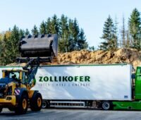 Im Bild ein Lkw von Zollikofer, der Holzspäne im Wald lädt, das Unternehmen hat Reko gekauft.