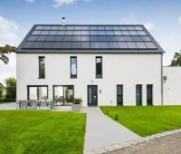 Zu sehen ist ein vorbildliches Gebäude mit einem Solarenergie-Dach, das Anforderungen einer möglichen Novelle des Gebäudeenergiegesetzes bereits heute spielend erfüllt.