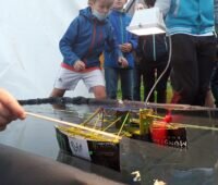 Zu sehen ist ein Miniatur-Solarboot, das auf einer Fahrrinne fährt. Der 14. Schleswig-Holstein Solarcup findet am 26. Juni statt.