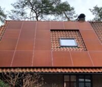 Im Bild ein Dach mit roten Photovoltaik-Modulen, Greenakku bietet farbige Photovoltaik-Module an.