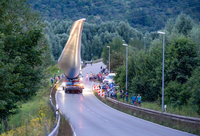 Transport eines Rotorblattes für Windturbine über eine Landstrasse mit Schaulustigen.